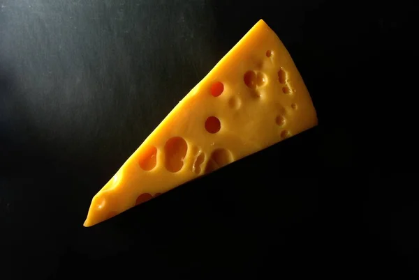 Koyu Bir Arkaplanda Delikleri Olan Bir Dilim Peynir — Stok fotoğraf