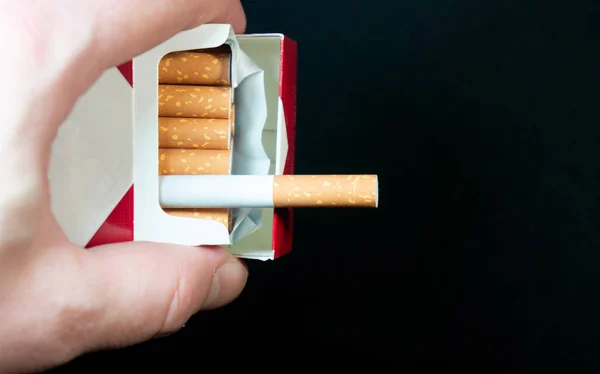 hand with a pack of cigarettes offers treat a cigarette