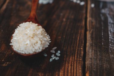 Tahta bir arka planda tahta bir kaşıkta bir torba kumaş ile Türk çiğ pirinç taneleri.