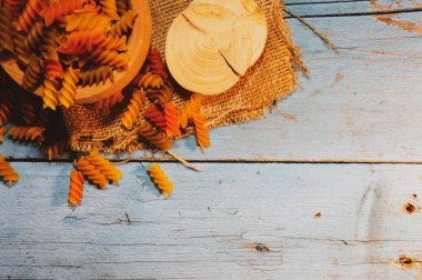 Tahta mavi bir masada ıspanaklı ve domatesli çiğ buğday renginde makarna.