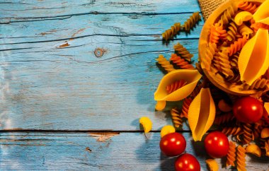  Farklı renkte makarna ve domatesli düz kompozisyon, metin için boşluk. Kurutulmamış bütün makarna.