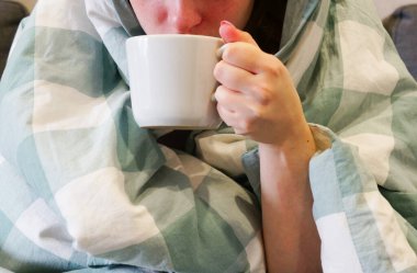 Elinde kupayla battaniyeye sarılmış kız grip olmuş.