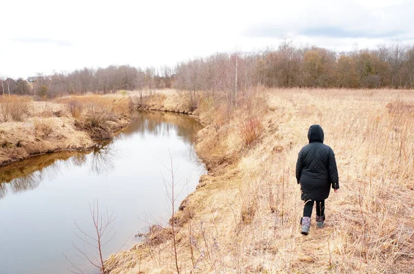 少女は川沿いの乾いた草の上を歩き — ストック写真