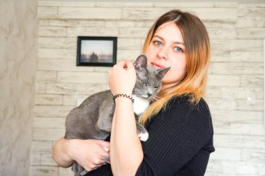 Kız sevgili kediyi kollarında tutuyor.