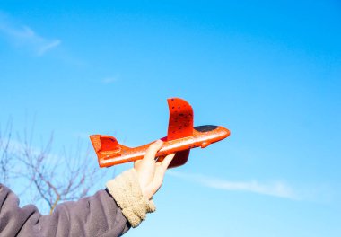 Gökyüzü arka planında oyuncak uçakla el, hava yolculuğu kavramı