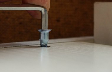  Mobilya montajı, Allen anahtarının yakın çekimi, mobilya vidası yonga tahtasına vidalanmış, iki tahtayı birbirine bağlayan vida. Montaj vidası delikteki deliğe vidalanmış.