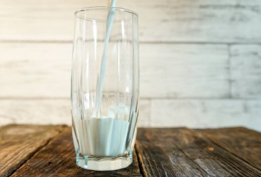 Süt, ahşap bir masada bir bardağa dökülür.