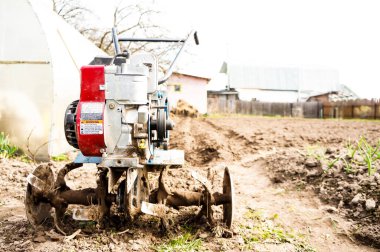 Çiftçi verimli toprağı gevşetiyor. Bahçedeki tarla ekimi için tarımsal makineler arka plandaki traktör tarlasında patates ekmek için.