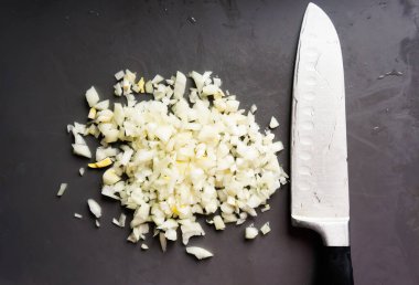  Kesme tahtasında bıçakla doğranmış soğanlar.