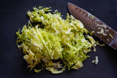  Kesme tahtasının üzerinde bıçakla doğranmış bir lahana kafası.