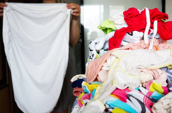 mom hangs baby clothes on the dryer