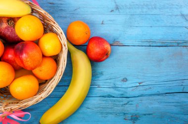  Mavi ahşap arka planda farklı meyveler içeren hasır sepet.