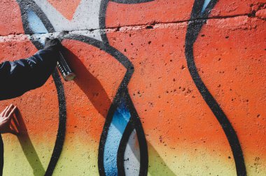 Sokak sanatçısı ortak bir duvara renkli graffiti çizer. Modern sanat konsepti, duvarına sprey boya sıkan el.