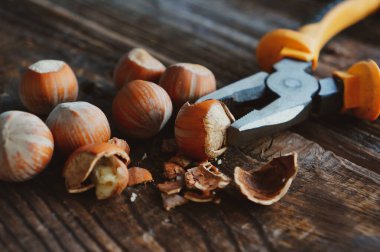 Tahta bir masada ceviz kırmak için bir sürü fındık ve kerpeten.