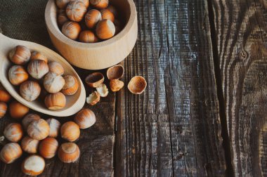 Fındık çekirdekleri ve bir kase odunla eski ahşap bir masada fındık dolu bir hayat. Metniniz için yer ile