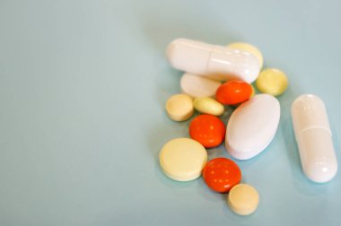 Mavi arka planda çeşitli şekillerde çok renkli haplar, reçeteli ilaçlar, mavi bir arka planda mesajınız için yer var.