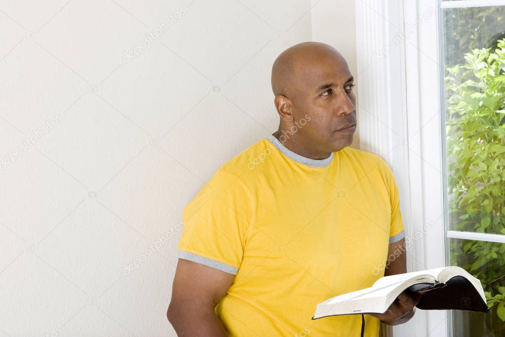 African American man sitting on a sofa and reading.
