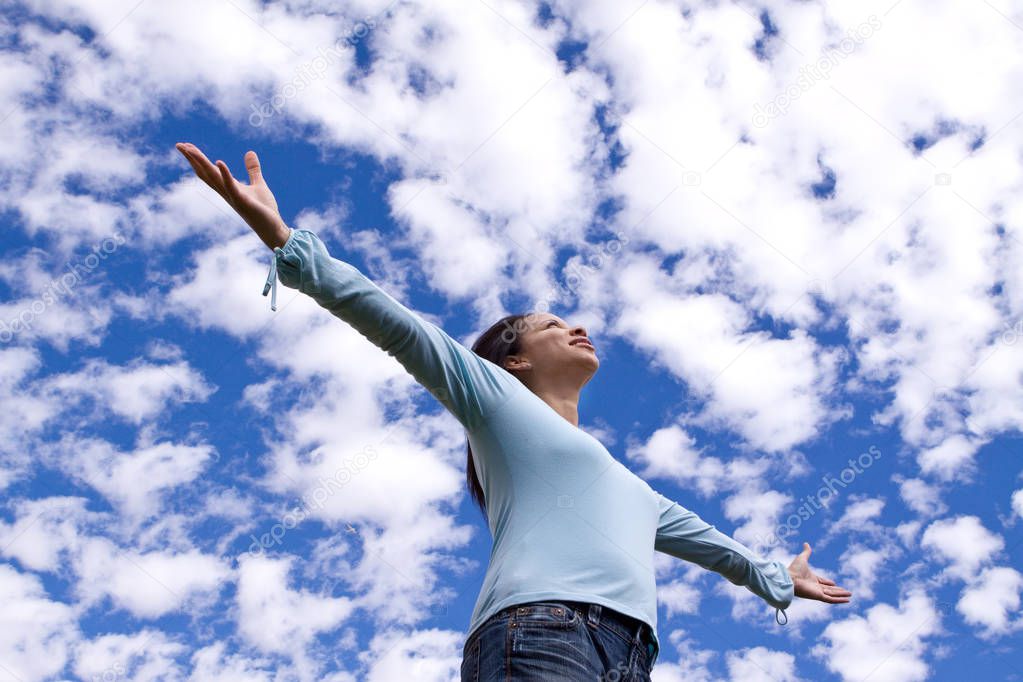 Happy woman standing outside with open arms.