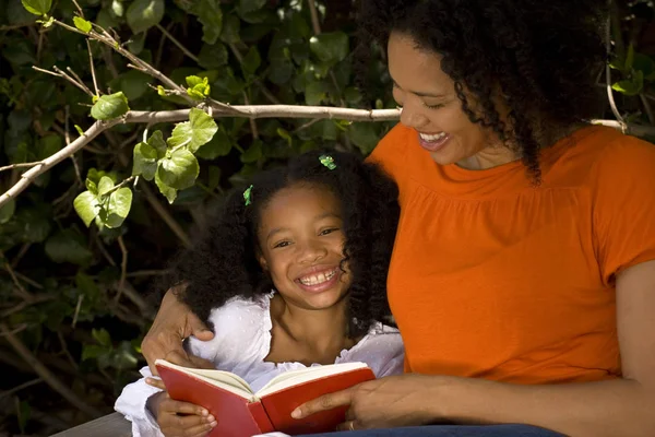 Amorosa mãe afro-americana lendo com sua filha . — Fotografia de Stock