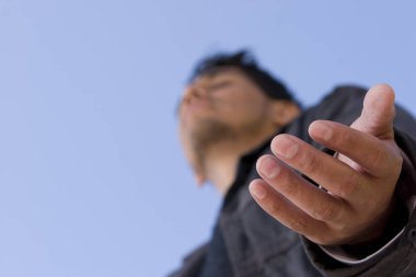 Hispanic man with open arm in prayer. clipart