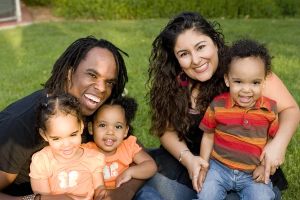 Happy biracial family with triplets at a park. — Stock Photo, Image