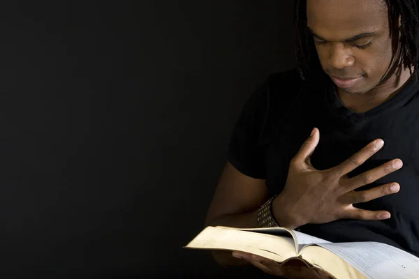 Hombre leyendo una biblia aislada en negro . — Foto de Stock