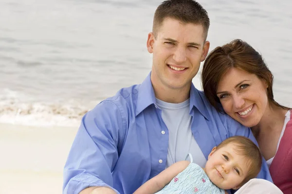 Junge Familie vergnügt sich draußen am Strand. — Stockfoto