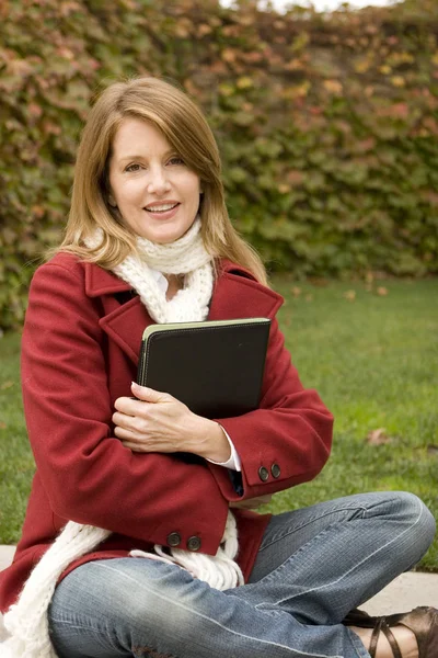 Woman sitting outside writing in a notebook.