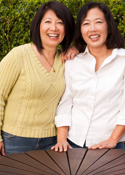 Mature Asian sisters smiling and laughing.