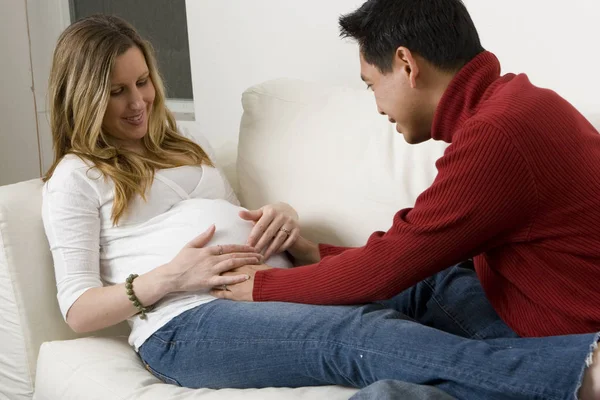 Husband embraceing his pregnant wifes belly. — Stock Photo, Image