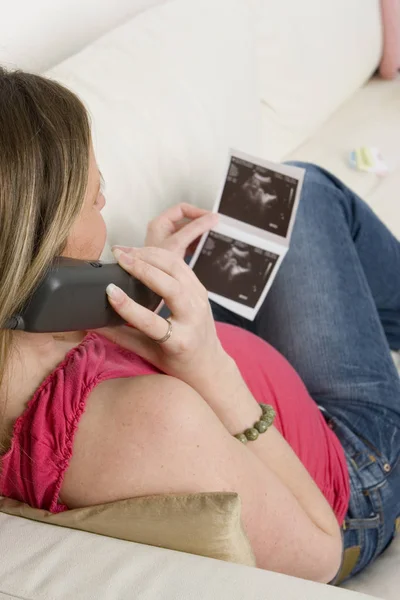 Mujer embarazada mirando una foto de ultrasonido de su bebé —  Fotos de Stock