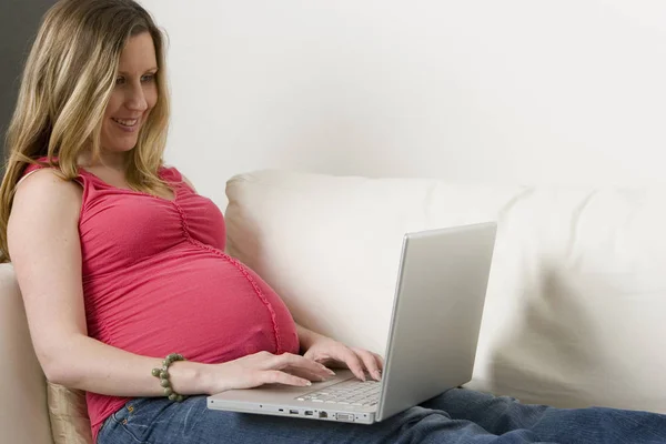 Mujer embarazada escribiendo en el ordenador . —  Fotos de Stock