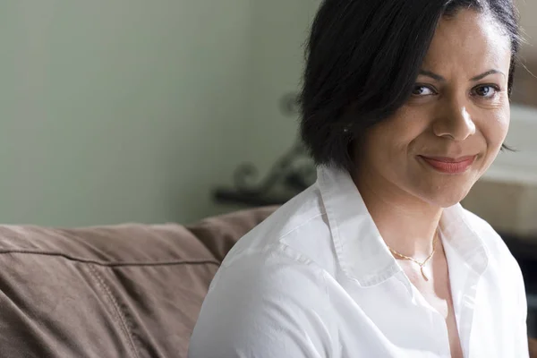 Mujer afroamericana confiada sonriendo sentada en el sofá . — Foto de Stock