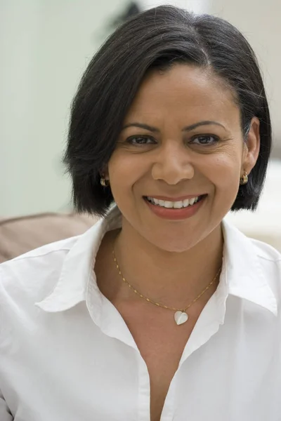 Mujer afroamericana confiada sonriendo sentada en el sofá . — Foto de Stock