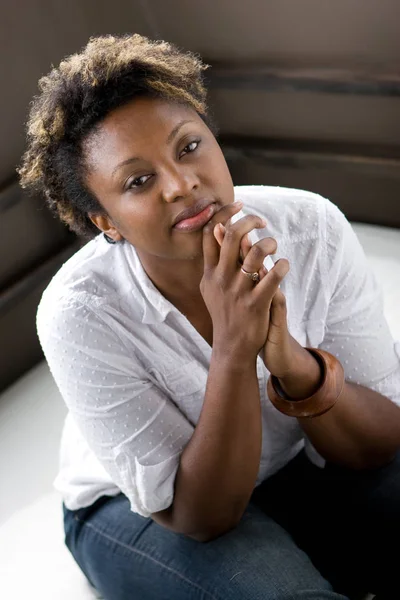 Selbstbewusste Afroamerikanerin sitzt auf Sofa. — Stockfoto