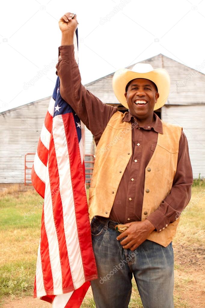 African American cowboy holding an American flag.