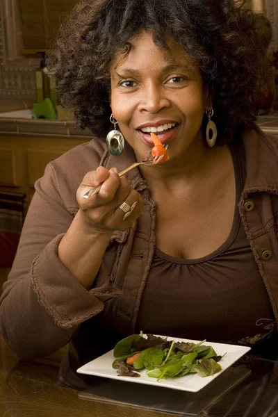 Donna afroamericana sorridente mangiare un'insalata . — Foto Stock