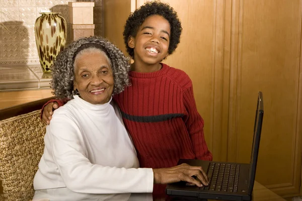 Gandmother e neto digitando em um laptop em sua casa . — Fotografia de Stock