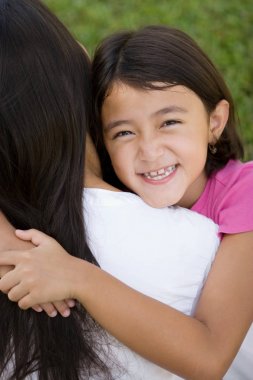 Sevgi dolu Asain anne ve kızı gülümseyen.