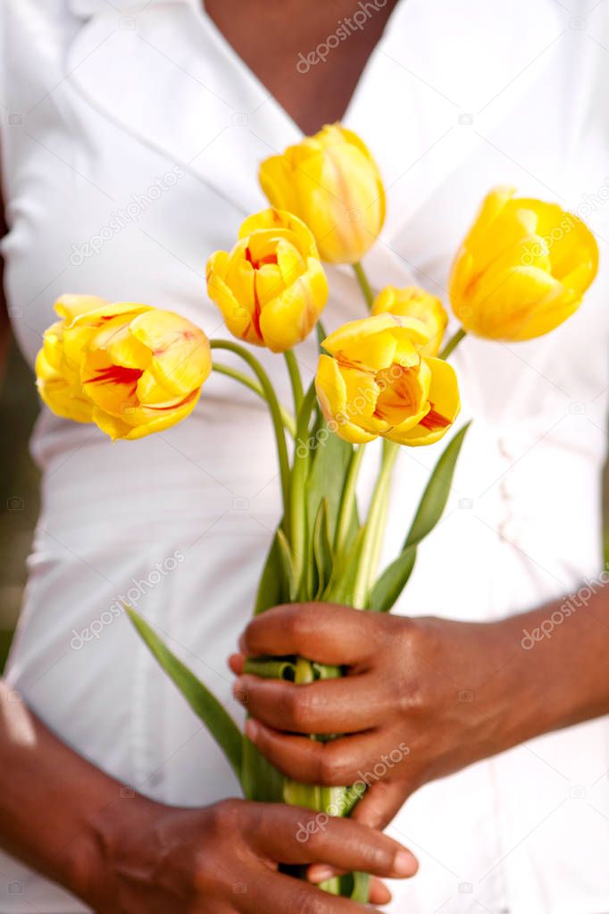 African American woman holding beautiful yellow flowers.
