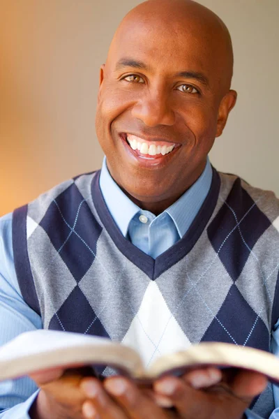 Hombre afroamericano sentado en un sofá leyendo . — Foto de Stock