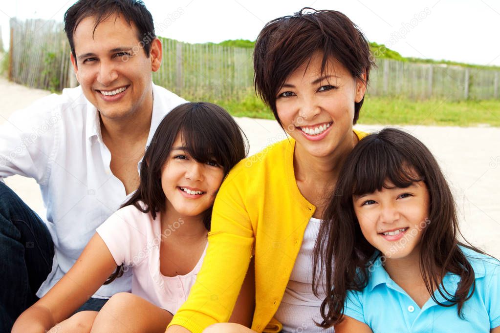 Asian family laughing and playing at the beach.