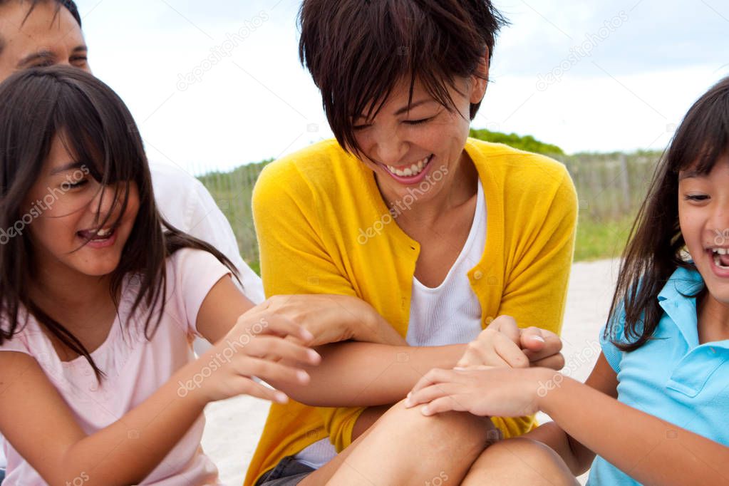 Asian family laughing and playing at the beach.