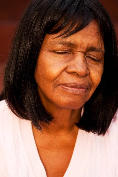 祈っているベンチに座っている年配のアフリカ系アメリカ人の女性. — ストック写真