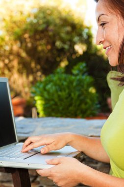 İspanyol kadın bir bilgisayarda yazarak dışarıda gülümseyen.