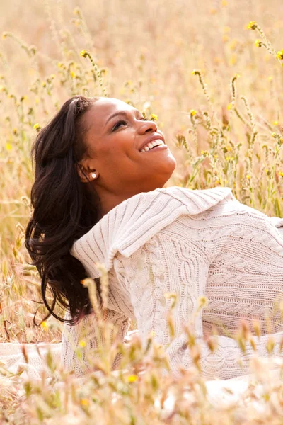 Mujer feliz sentada en un campo sonriendo . — Foto de Stock