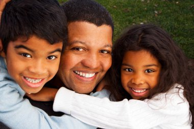 Biracial aile gülüyor ve dışarıda gülümseyen.