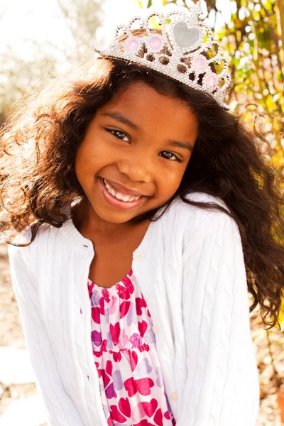 Linda niña sonriendo usando una tiara . — Foto de Stock