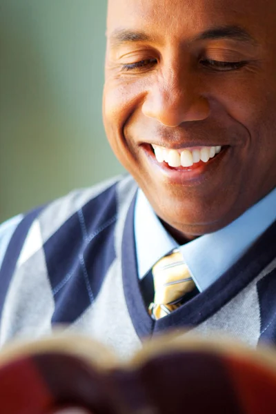 Hombre afroamericano sentado en un sofá leyendo . — Foto de Stock