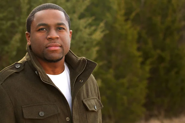 Junger afrikanisch-amerikanischer Mann lächelt draußen. — Stockfoto